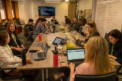 group of people around a table with whiteboards and screens