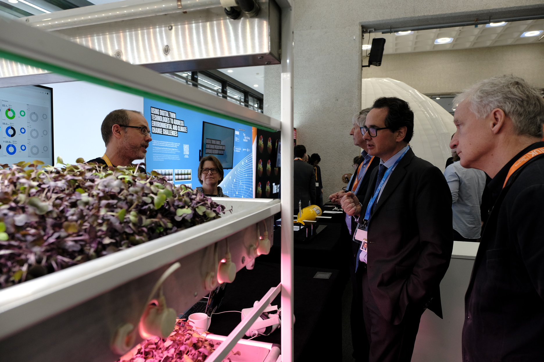 Viscount Camrose speaking to researcher at an exhibition stand about an underground farm