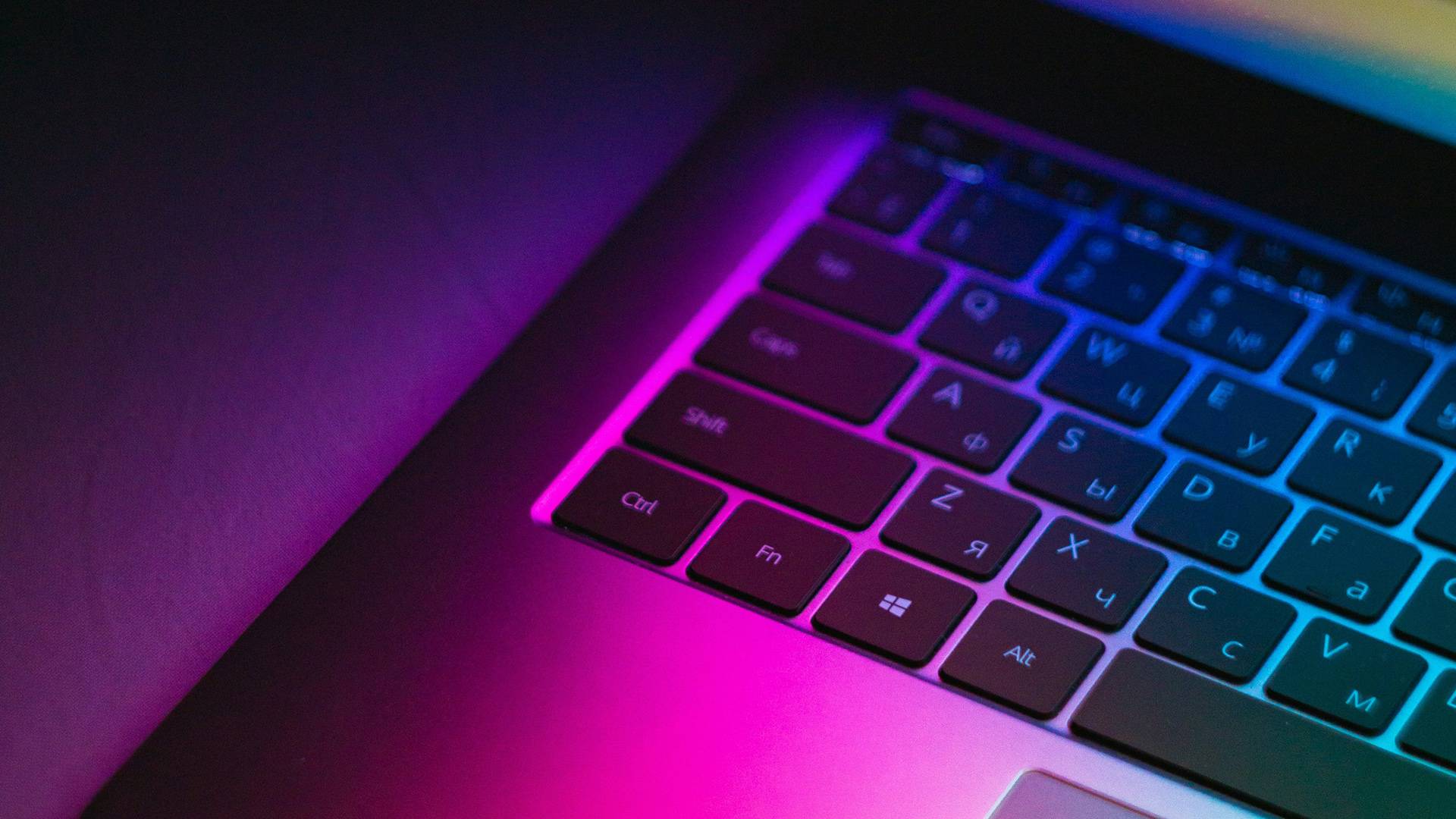 Close-up of laptop keyboard in neon light