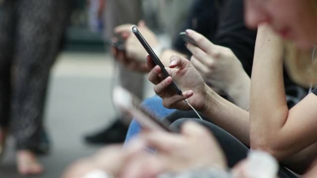 Row of people sitting looking at their phones